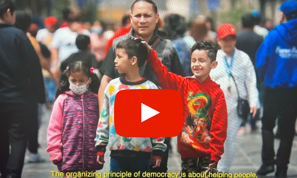 Family walking in a crowd in Peru. Play button super imposed over image.